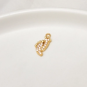Dettaglio del ciondolo a forma di piede con micro-zirconi dorati per creazione gioielli