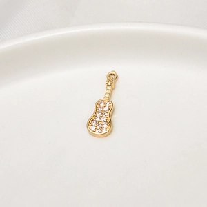 Dettaglio macro di un ciondolo a chitarra dorato con zirconi per creazioni di gioielli