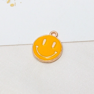 Macro detail of a bright yellow smiley face pendant with gold plating for DIY jewelry