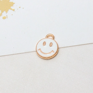 Detailed close-up of a golden metal smile pendant with white enamel finish for DIY jewelry