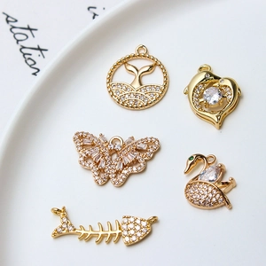 Gold plated copper charms set with CZ inlay featuring dolphin butterfly and fishbone shapes