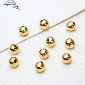 Macro shot of 10 gold-plated round spacer beads on a textured white fabric background