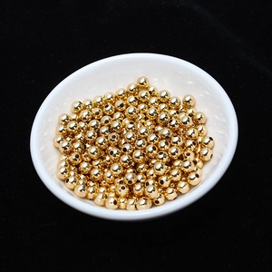 Close-up of polished 18K gold-plated spacer beads in a white dish for DIY jewelry