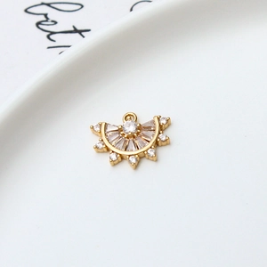 Detail van waaiervormige gouden hanger met zirkonia op een wit keramisch dienblad