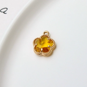 Détail d'un pendentif fleur de 12mm plaqué or avec pierre facettée jaune et bordure
