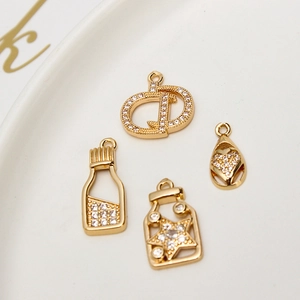 Macro shot of gold-plated charms with micro-zirconia in heart and bottle shapes