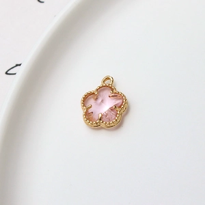 Gros plan d'un pendentif fleur à cinq pétales doré 12mm avec une pierre rose clair