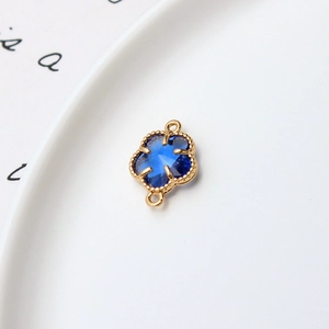 Détail macro d'un connecteur trèfle 12mm doré avec gemme bleue pour bijoux DIY