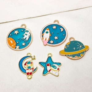 Macro view of assorted space-themed enamel charms including astronaut and rocket designs