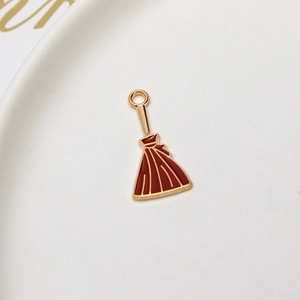 Detailed macro view of a magical broom pendant with gold plating and burgundy enamel inlay