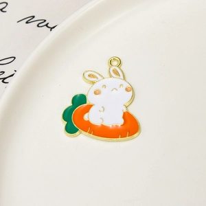 Macro view of cute enamel bunny on carrot charm with bright gold alloy edges for DIY jewelry