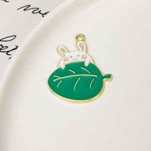 Detail of DIY white rabbit and green leaf enamel pendant for jewelry making