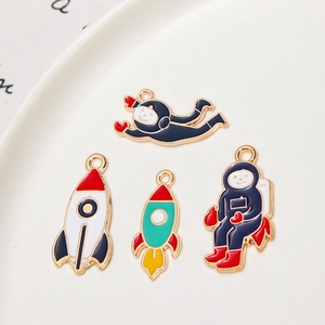 Detail of four enamel astronaut and rocket pendants for DIY jewelry making