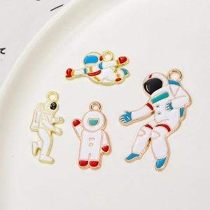 Astronaut enamel alloy pendants in four poses for DIY jewelry making on white ceramic plate