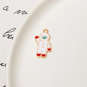 Detailed view of an enamel astronaut charm with gold accents on a white tray
