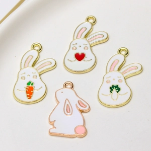 Detail view of cute white enamel bunny charms with gold metal edges for DIY jewelry making