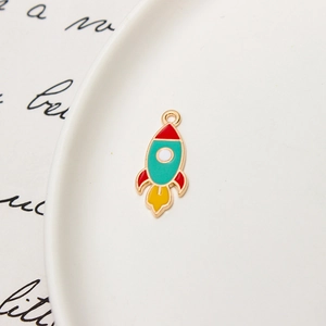 Macro detail of colorful enamel rocket pendant with gold trim for DIY jewelry making
