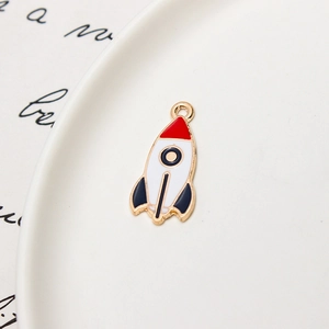 Detail of red and navy blue enamel rocket pendant with golden edges on white plate