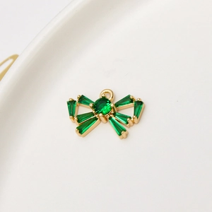 Macro-opname van gouden strikvormige hanger met smaragdgroene kristallen en oogje