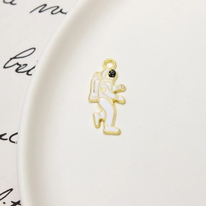 Macro detail of enamel astronaut charm in gold alloy on a white ceramic plate