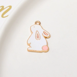 Macro view of white enamel rabbit charm with gold trim and pink details for DIY jewelry