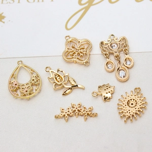 Detail of assorted gold-plated copper flower pendants with zircon for DIY jewelry making