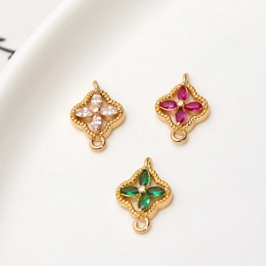 Detailopname van drie vergulde bloemconnectoren met gekleurde zirkoon voor DIY-sieraden