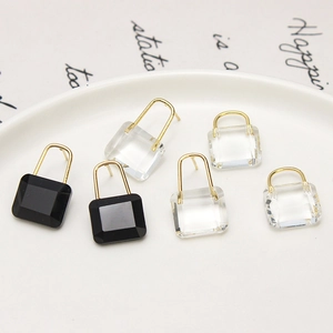Gros plan de boucles d'oreilles cadenas en cristal noir et transparent sur une assiette