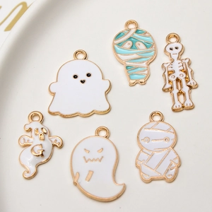 Enamel Halloween charms including ghosts, mummies, and skeleton on a ceramic plate
