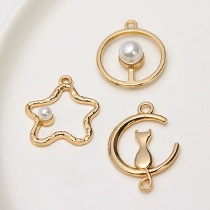 Macro shot of gold alloy charms with white pearls featuring cat, star and moon shapes