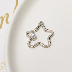 Detailed view of a silver star charm with rippled texture and an inlaid pearl