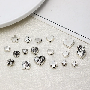 Flat lay of retro silver alloy beads with cross and heart designs for DIY jewelry