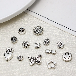 Macro detail of assorted vintage silver charms including heart, butterfly and clover designs