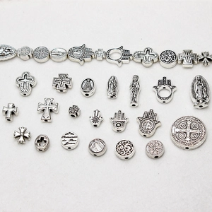 Macro view of vintage silver religious charms including Hamsa, crosses, and medals