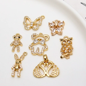 Dettaglio di sette ciondoli animali in oro con micro-zirconi incastonati su piatto bianco