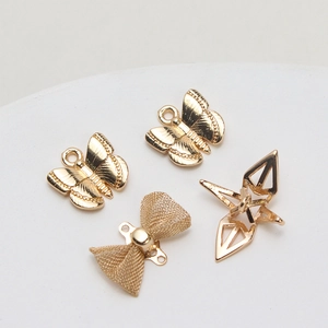 Detailed view of gold plated butterfly, bowknot, and paper crane DIY jewelry charms