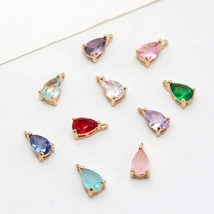 Detailed view of colorful teardrop crystal charms with gold prong settings and jump rings
