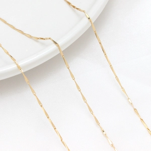 Macro shot of 14K gold-plated twisted link chain showing delicate glossy texture