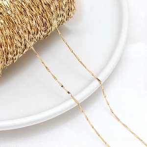 Macro shot of 14K gold plated bamboo link chain on white spool for jewelry making