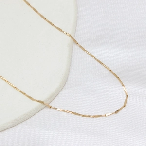 14K gold plated minimalist geometric link chain necklace on a white ceramic plate