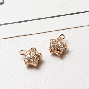 Macro view of two gold-plated star pendants with sparkling cubic zirconia settings