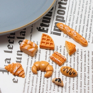 Macro detail of nine miniature resin bakery charms including croissants and baguettes