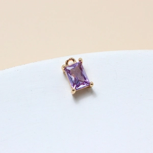 Macro shot of a purple rectangular glass pendant with a gold setting and bail for jewelry