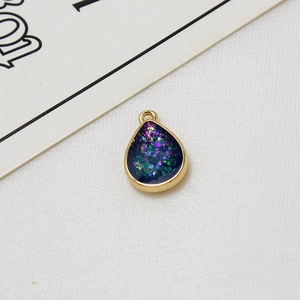 Nahaufnahme von tropfenförmigem vergoldetem Anhänger mit Glitzerharz für DIY-Schmuck