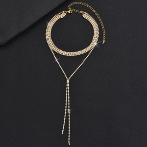 Λεπτομέρεια χρυσού κολιέ με φούντες, λαμπερά στρας και κούμπωμα καβουράκι