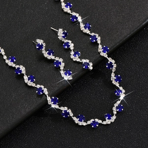 Macro detail of silver plated necklace and earrings set with deep blue crystals on leather