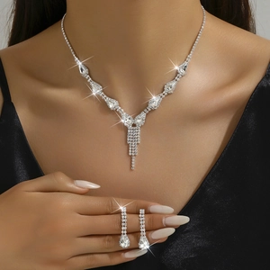 Macro detail of teardrop crystal necklace and fringe earrings set on a model