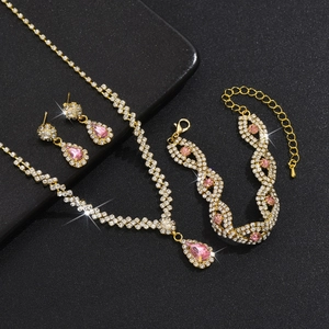 Nahaufnahme eines goldenen Brautschmuck-Sets mit funkelnden rosa Tropfenkristallen und Quasten