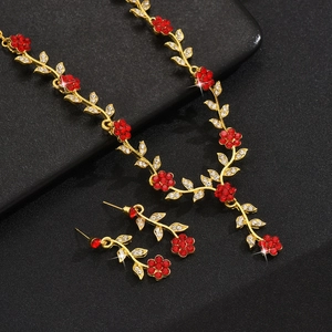 Parure de bijoux fleurs dorées avec strass rouges et feuilles de cristal sur cuir noir