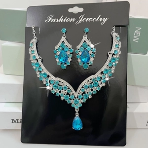 Macro detail of V-shaped silver alloy necklace and teardrop earrings set with blue gems